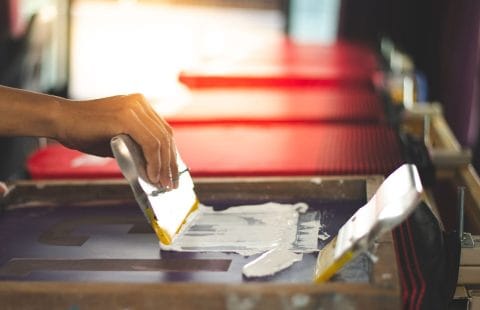 عملية الطباعة بالشاشة الحريرية الاحترافية باستخدام مواد الطباعة بالشاشة الحريرية، وألواح الطباعة، والمعدات المساعدة.